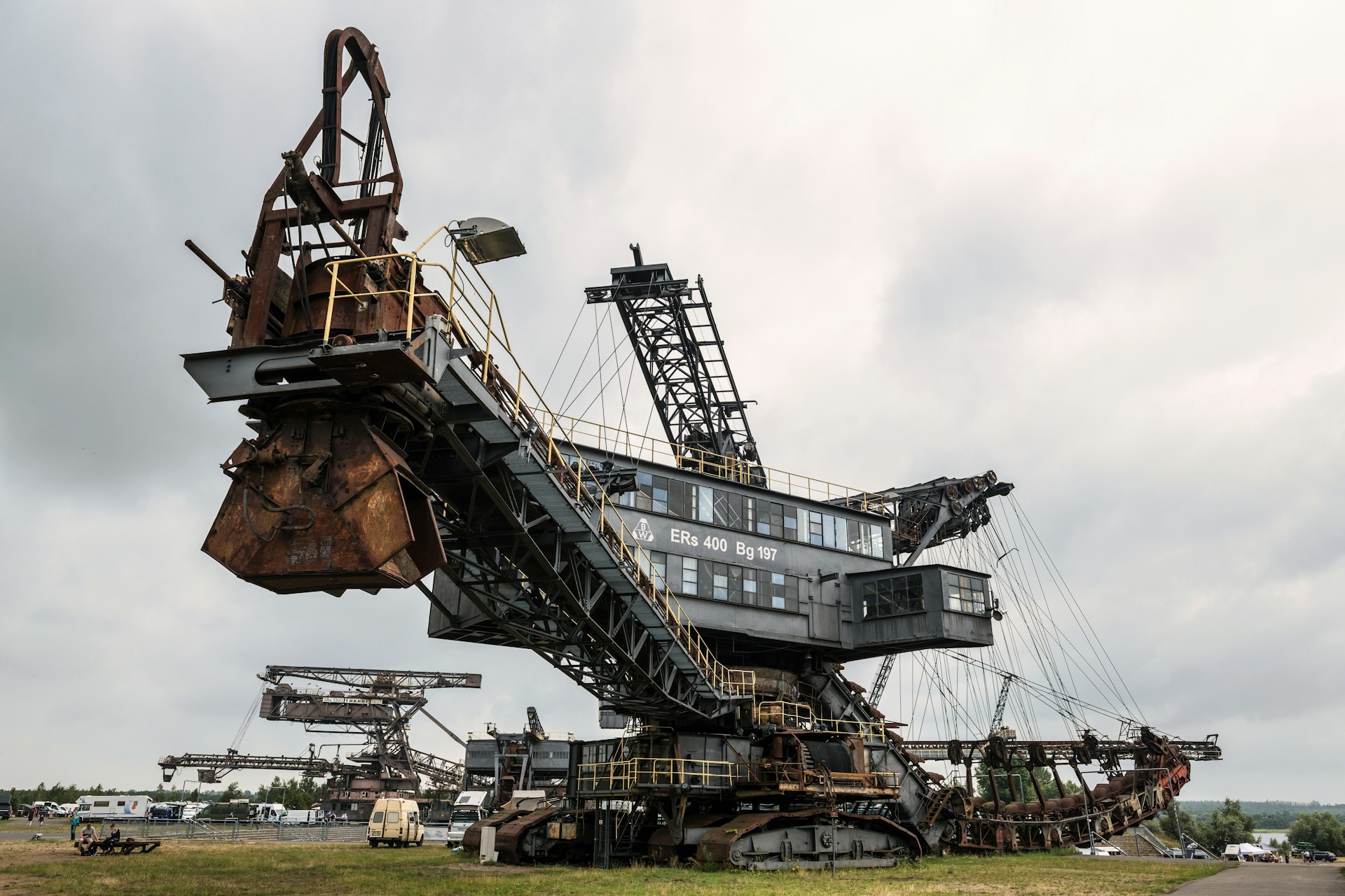 Giant rusty excavator in a field under cloudy sky